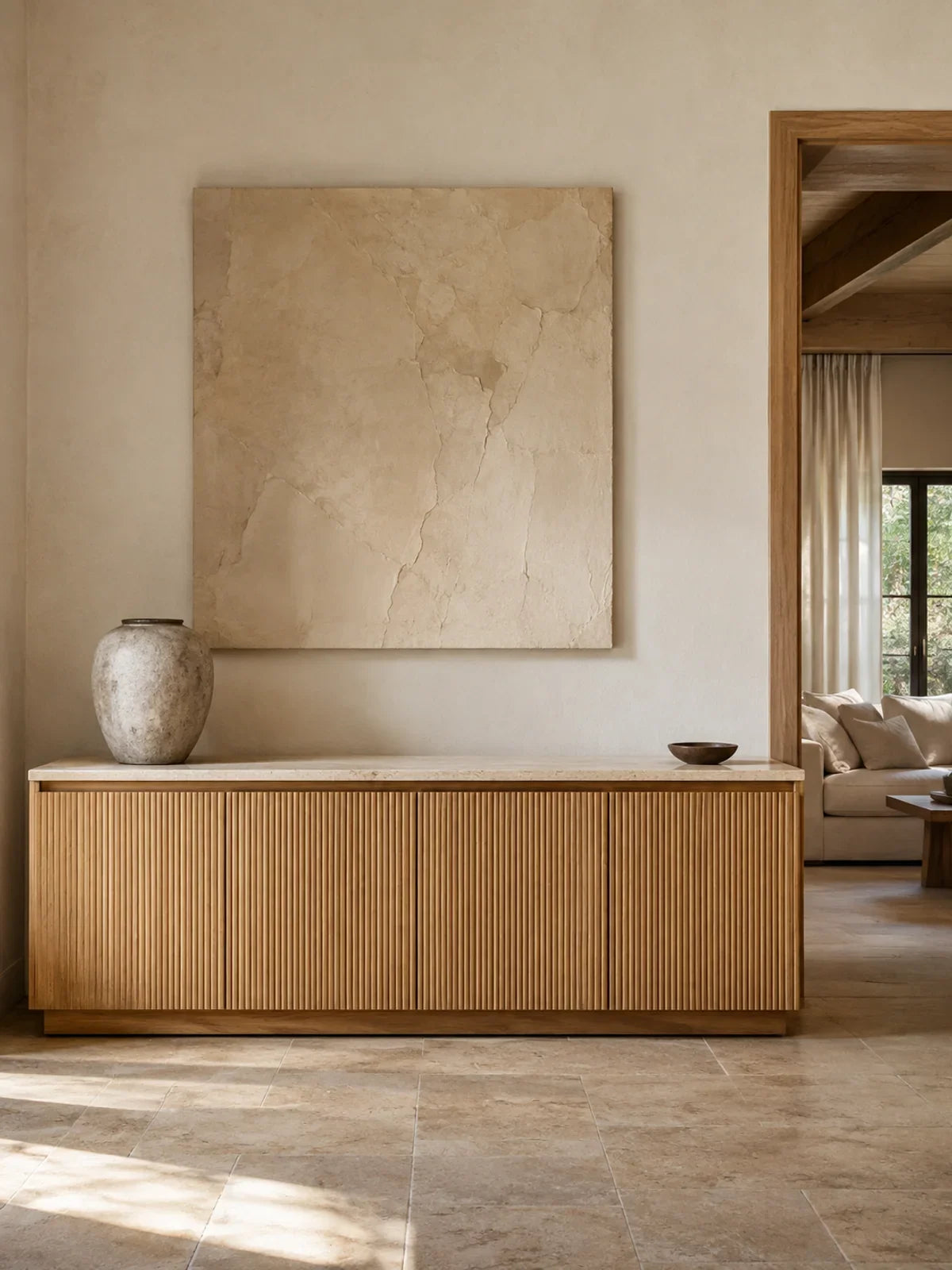 A long oak sideboard with precise ribbed timber doors and a thick lightly veined cream stone top, photographed almost front-on in an elegant hallway.