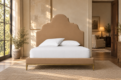 Lifestyle view: Camilla upholstered bed with aged brass base in a warmly lit bedroom
