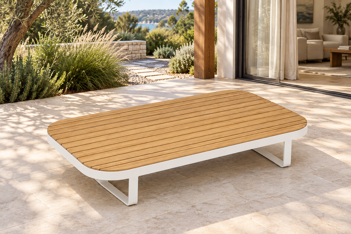 Lifestyle view: Vela modular aluminium coffee table on a garden terrace beside a furnished home.