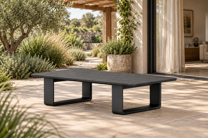 Lifestyle view: Zenia aluminium coffee table on a planted terrace beside a furnished home.