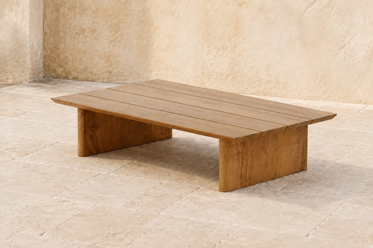 Vela Coffee Table in Teak, photographed in a quiet outdoor courtyard