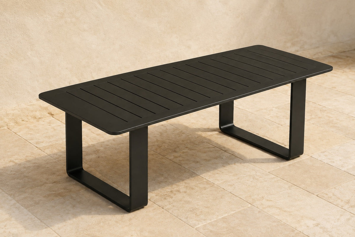 Zenia Dining Table in Aluminium, photographed in a quiet outdoor courtyard