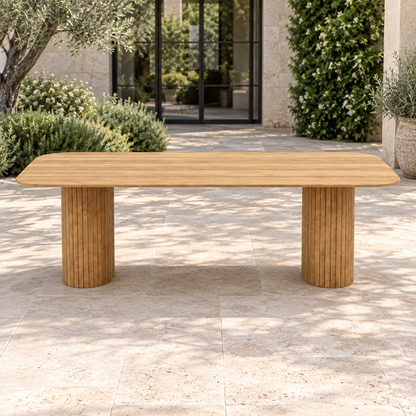 Lifestyle view: Ethereal Dining Table in Teak, frontal view of the 214 cm size in a planted home courtyard