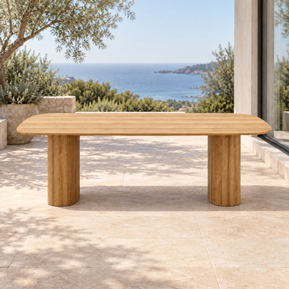 Lifestyle view: Ripple Dining Table in Teak, straight front view on a furnished coastal terrace